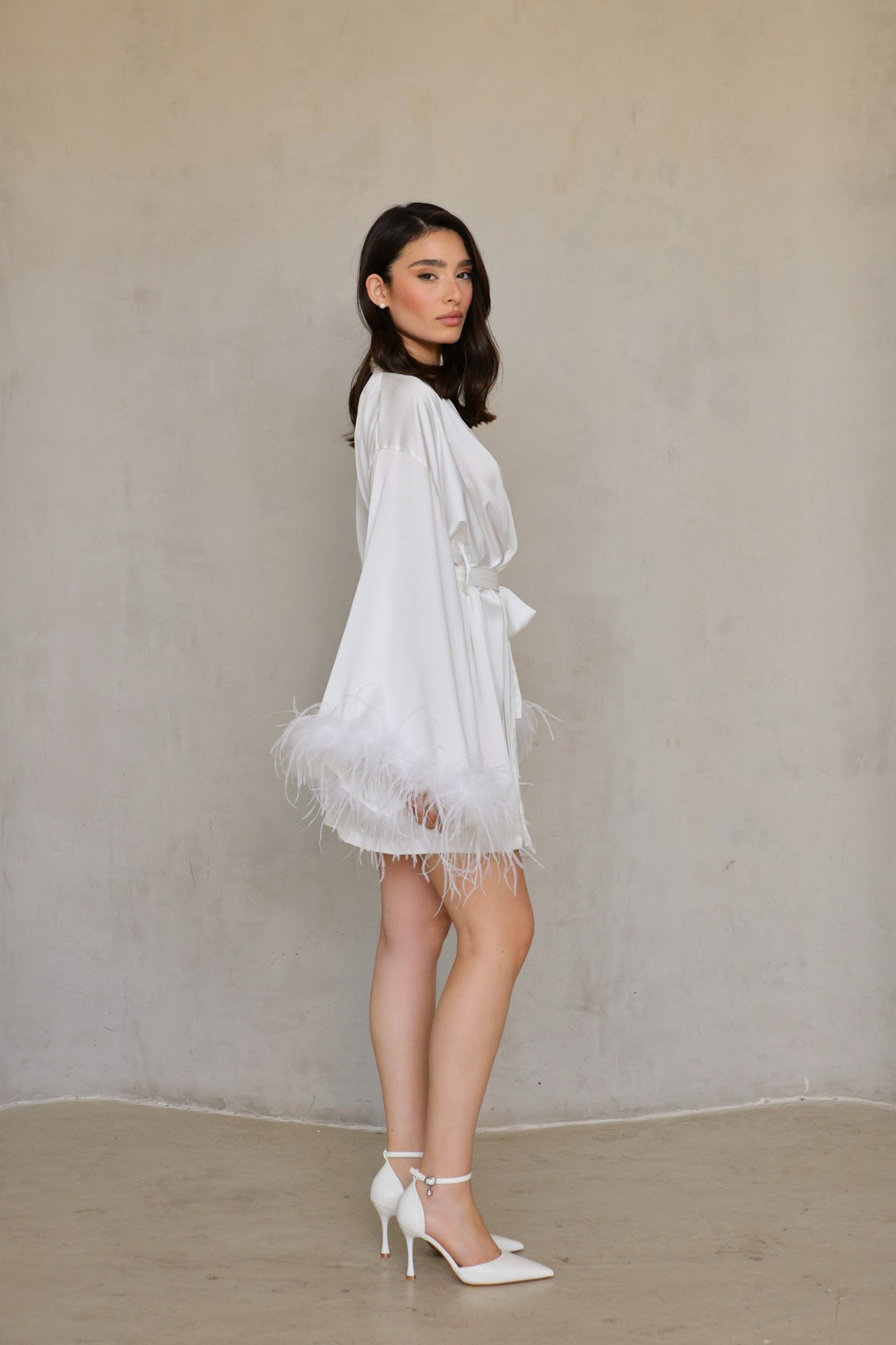 Swan robe in motion -model stepping forward, feathers flowing at cuffs and hem.