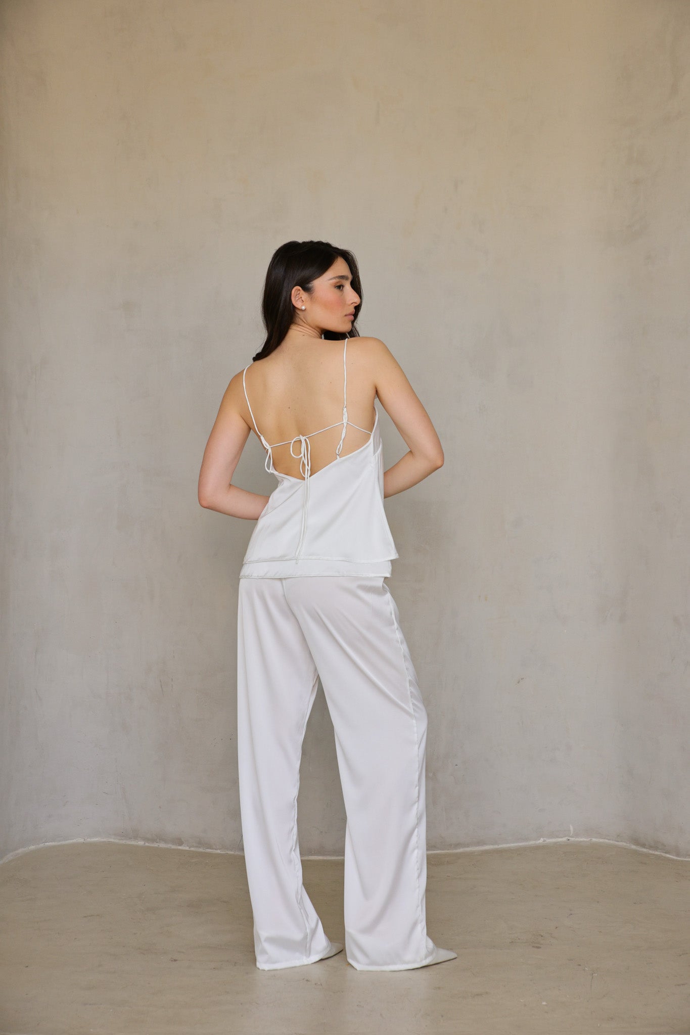 Alternate front view of Ivory Rose satin pants—model hands at waistband