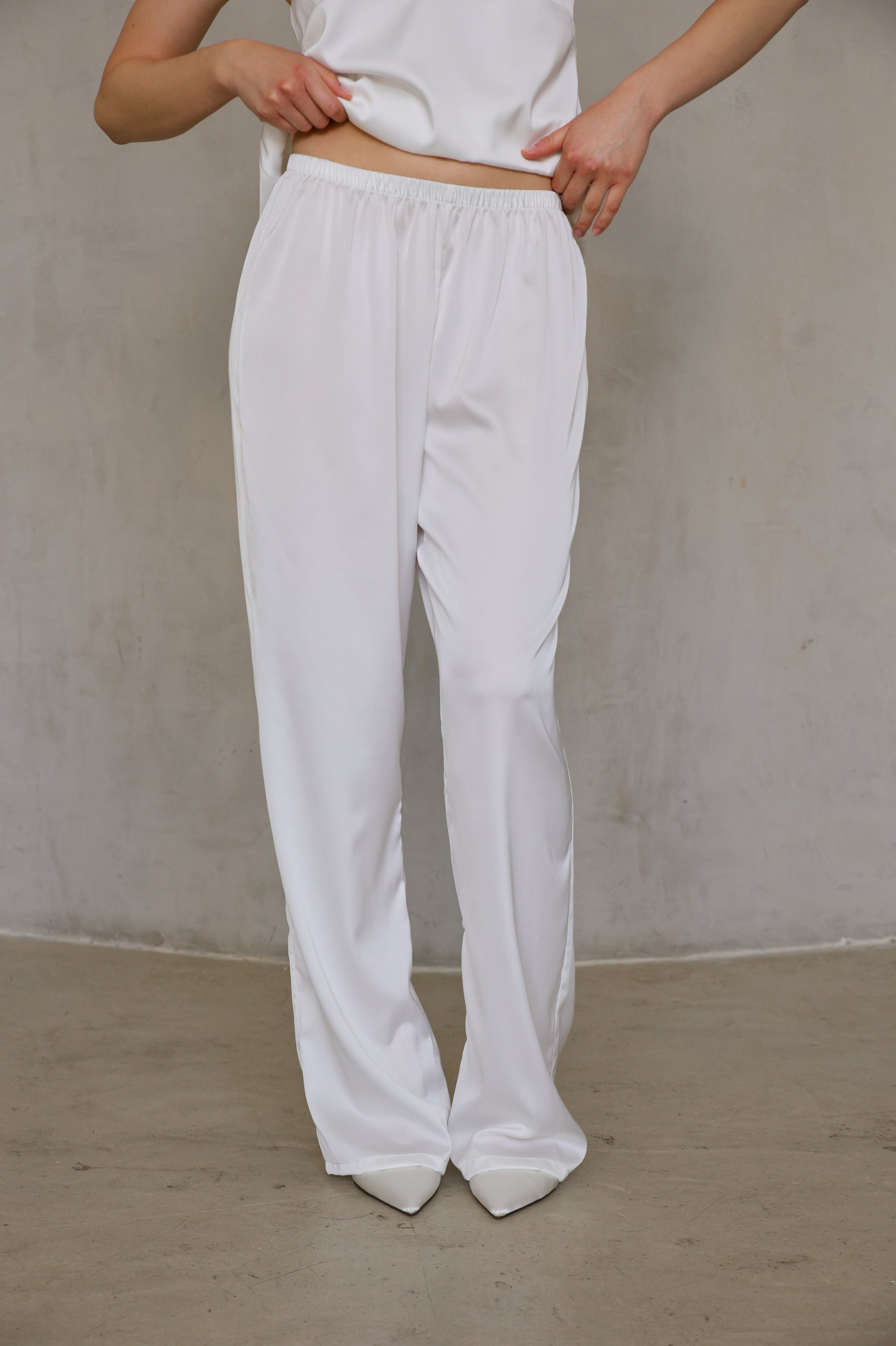 Close-up of Ivory Rose satin pants—elastic waistband and straight-leg drape, front view