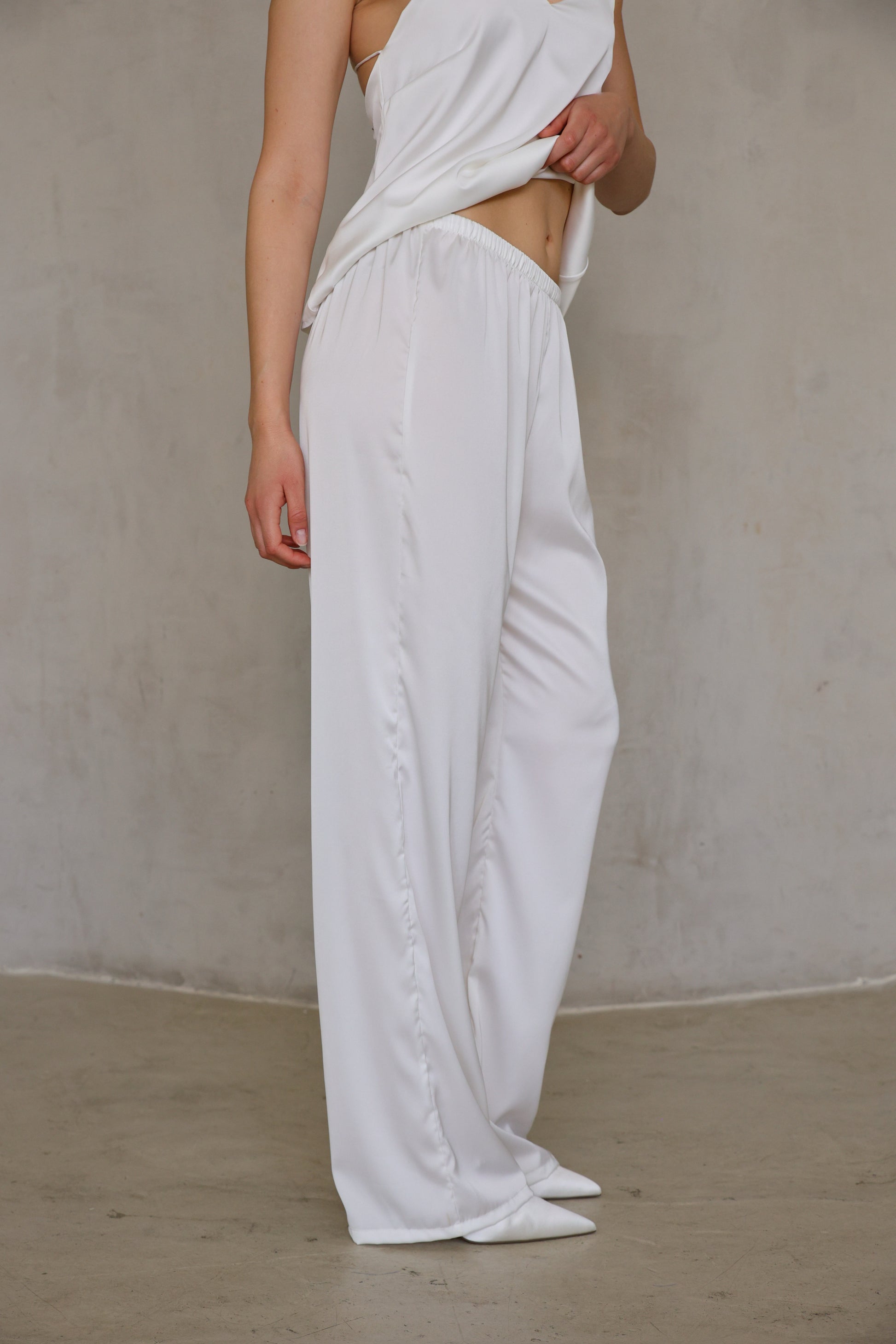 Ivory Rose satin pants side detail showing soft drape and ankle length, three-quarter view